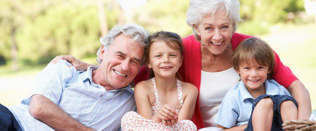 A family sitting on the ground with their arms around each other.