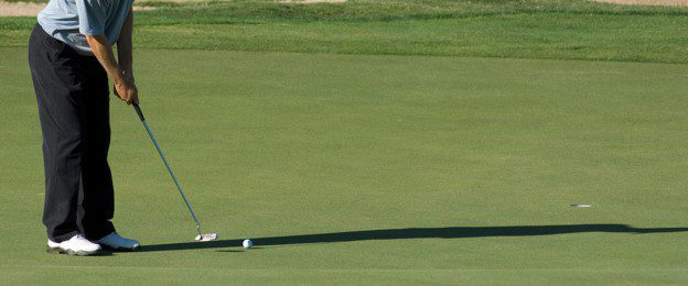 A golf course with a golfer on the green.