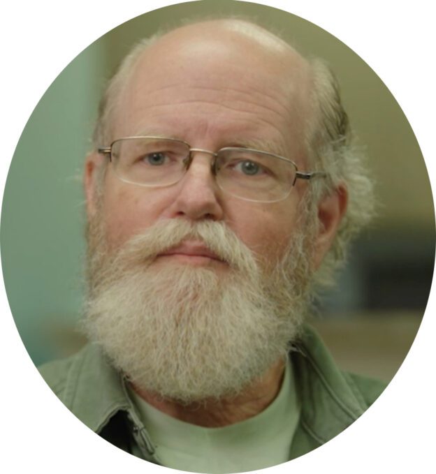 A man with a beard and glasses is wearing a green shirt.