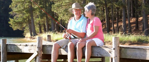 Senior couple fishing together on lakeside dock